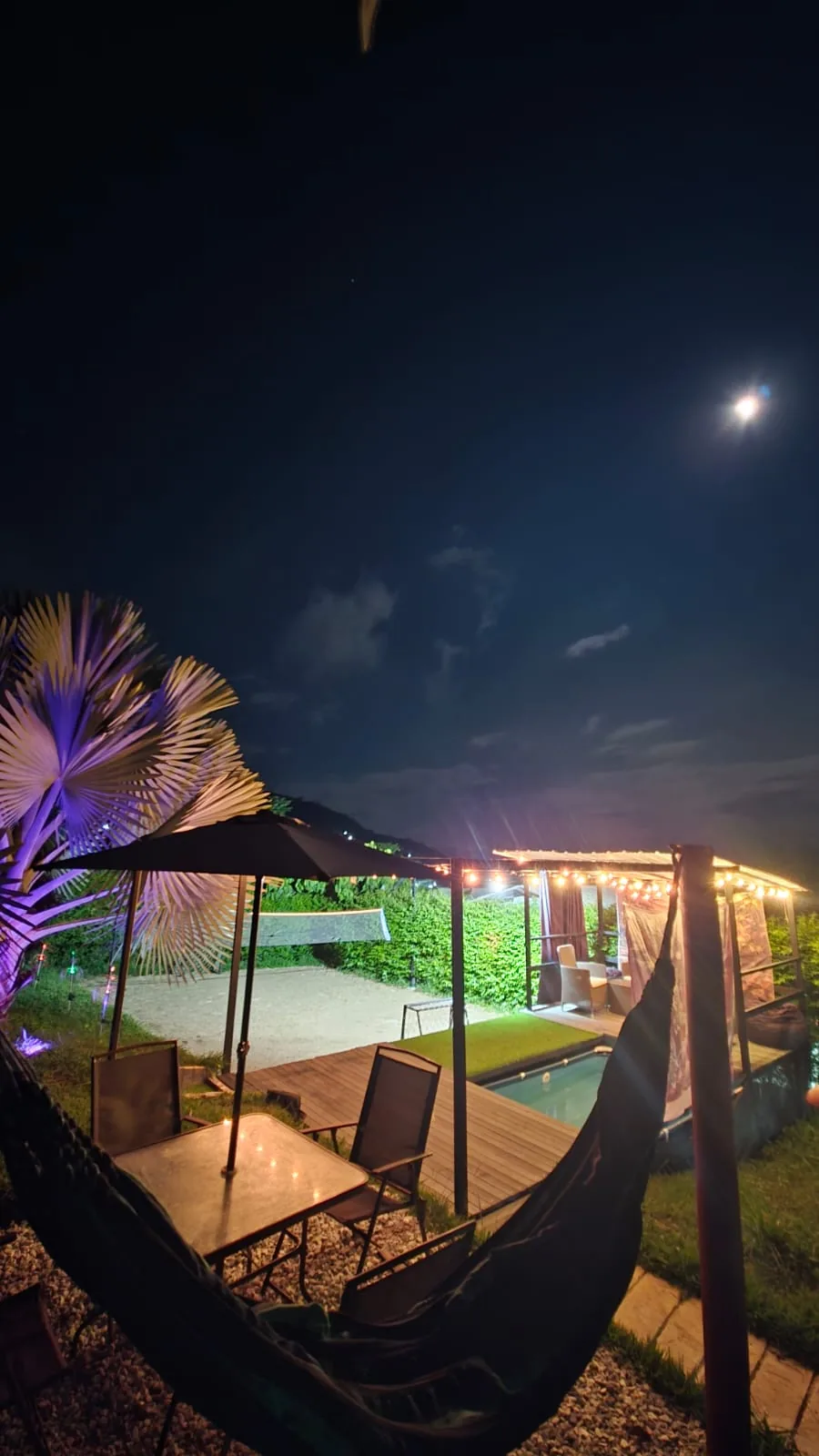 Zona de hamacas y piscina de noche bajo la luna en Gualanday Glamping